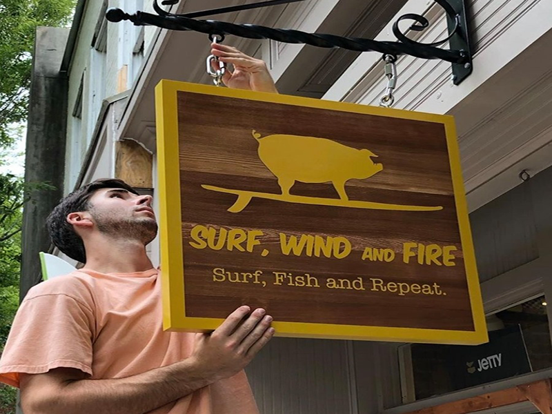 surf-wind-fire-storefront-employee-hanging-sign-new-bern-nc-image